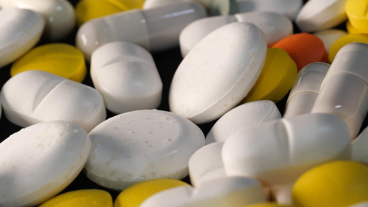 Assorted white and yellow medication tablets and capsules