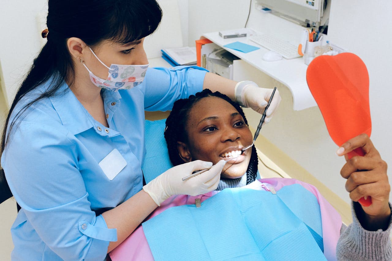 Patient checking their tooth in a handheld mirror while dentist assists