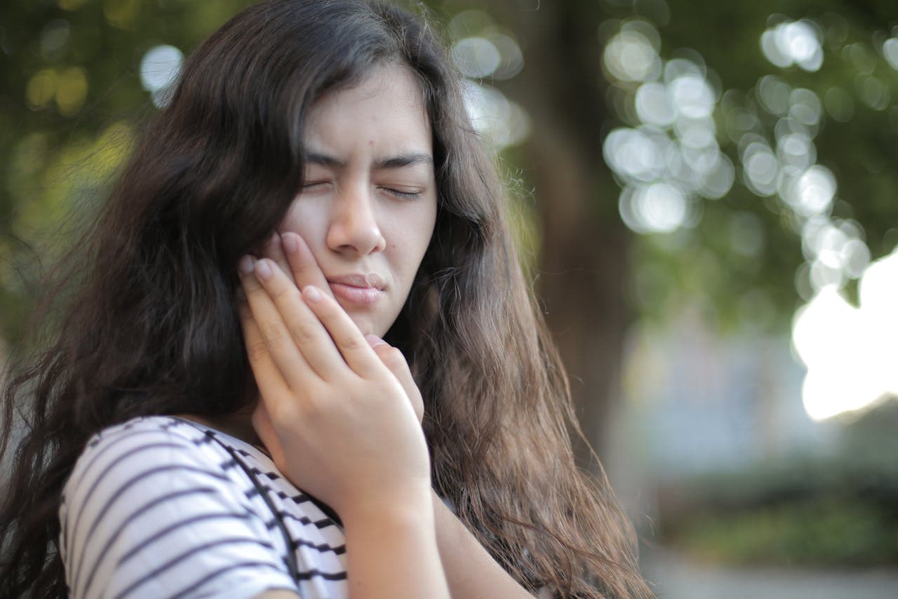 Person holding their cheek because of tooth pain