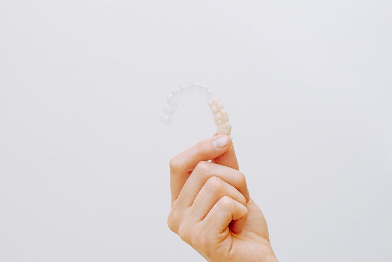 Hand holding a clear Invisalign aligner tray.