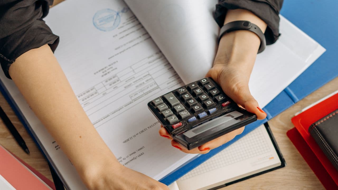Hand using a calculator over dental treatment paperwork