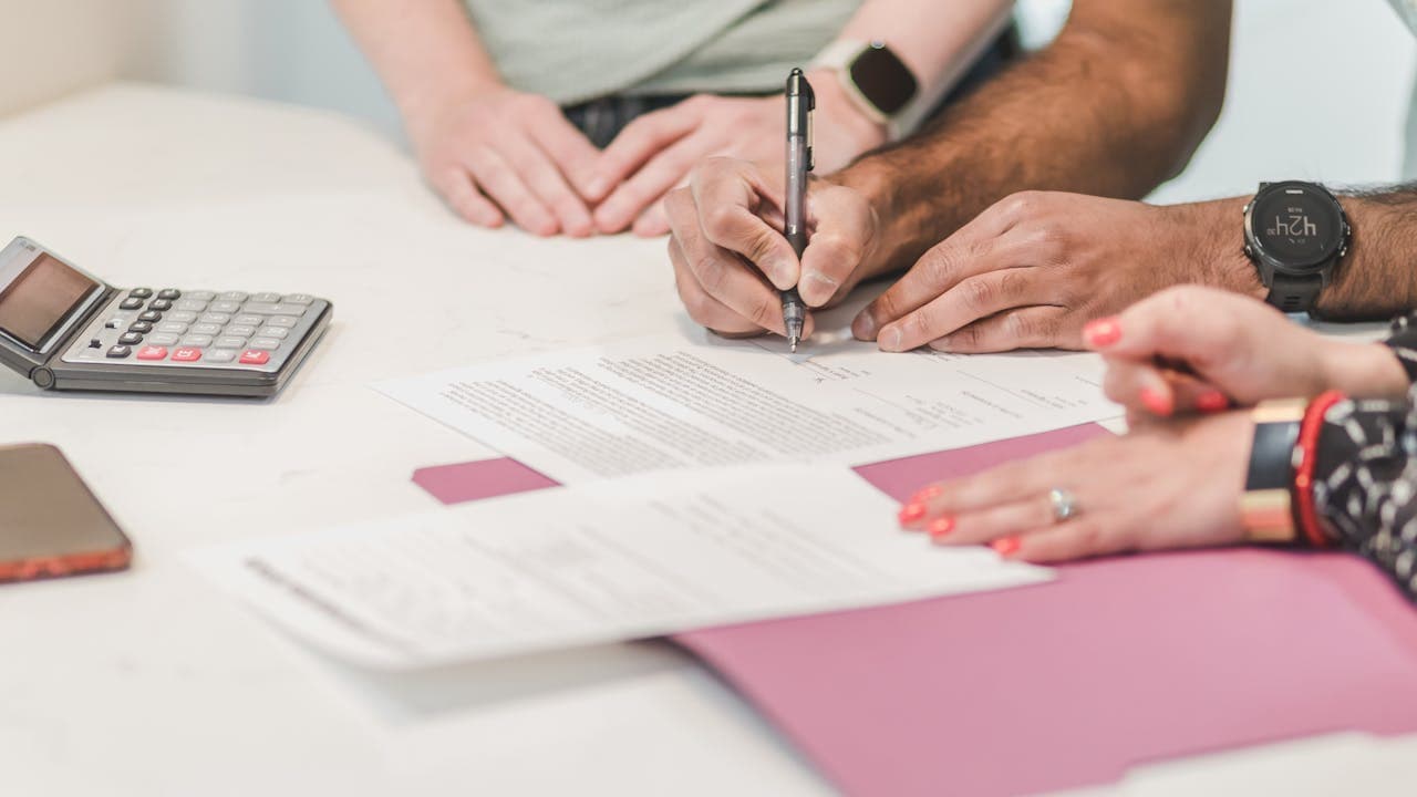 Two people reviewing insurance paperwork with a calculator at a desk